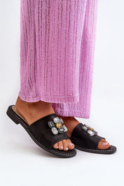 Person wearing Velinor Decor flat sandals with decorative accents, featuring a glossy synthetic upper and soft leather insole.