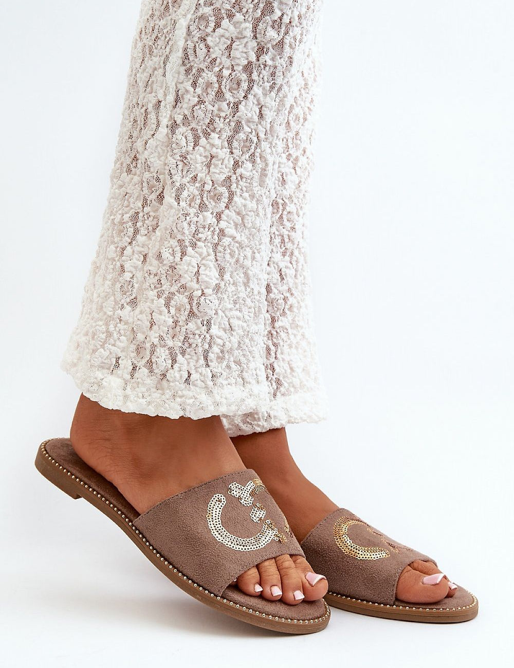 Person wearing Naerelle Suede Flip-Flops with sequin detail, paired with lace pants, highlighting casual summer style.