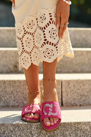 Woman wearing pink sequin suede flip-flops with low-profile heel and crochet skirt, perfect for summer style and comfort.