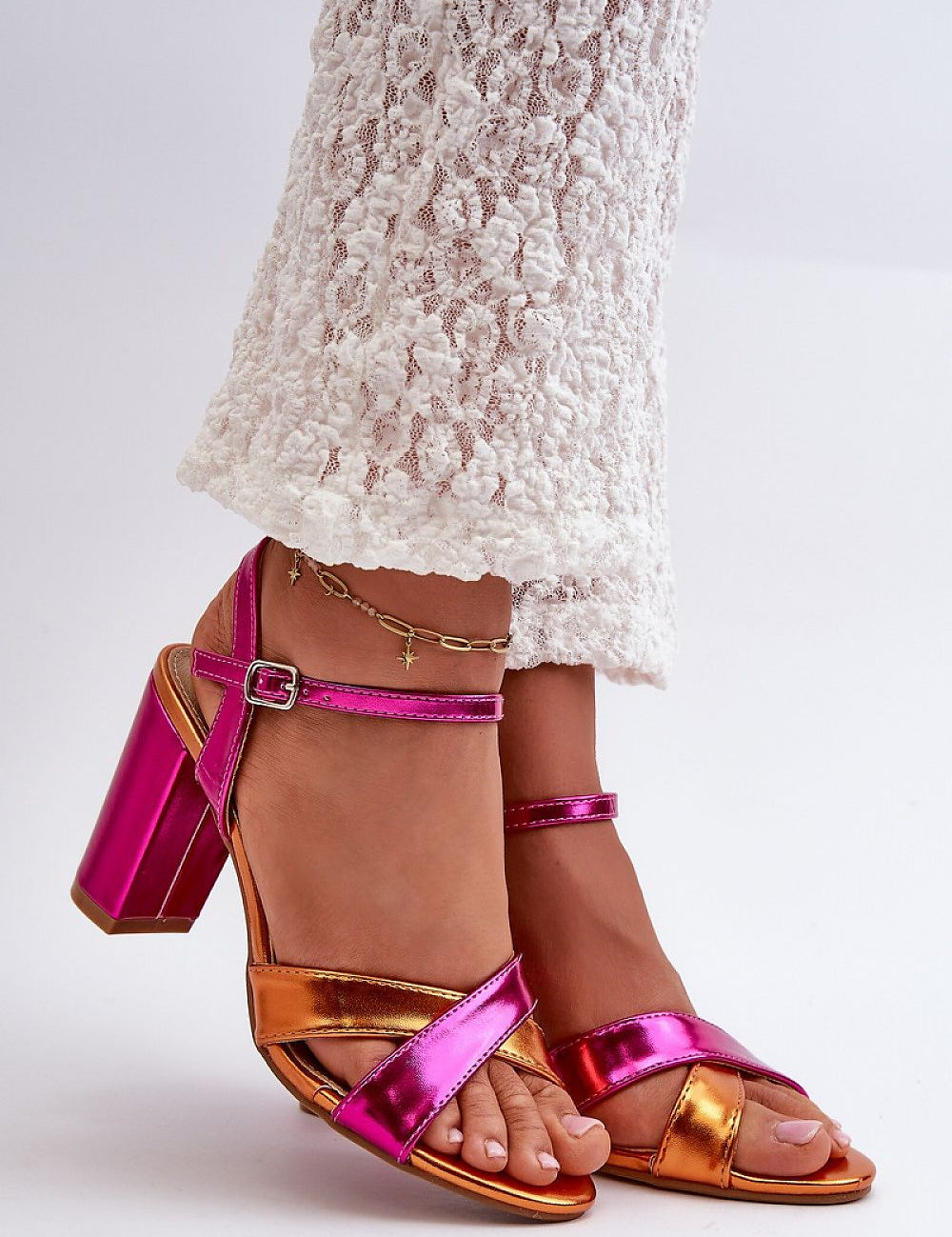 Colorful cross-strap heeled sandals with ankle buckle, worn with lace pants for a stylish summer look