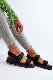 Woman wearing Rivexa Platform Strap Sandals with Velcro fasteners, black eco leather, and platform sole, paired with light jeans.