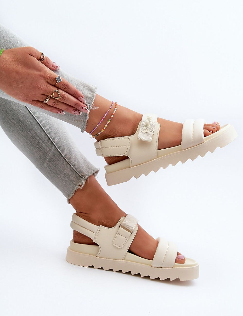 Alt Tag: Woman wearing cream Rivexa platform strap sandals with eco leather, paired with gray jeans and anklets, highlighting comfort and style.