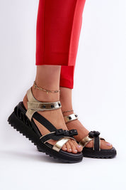 Aurelline Strap Bow Wedge Sandals with gold and black design, featuring bow detail, worn with red pants and ankle accessories