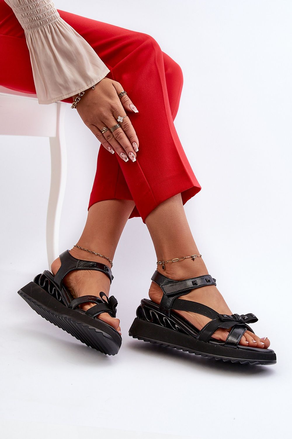 Woman wearing Aurelline Strap Bow Wedge Sandals with artificial leather upper, Velcro strap, and delicate bow detail, sitting on chair.