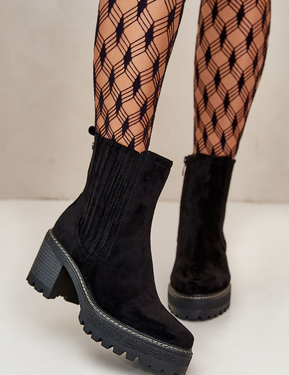 Aurevyn Hollowrise Cold Poise black ankle boots with block heel and rounded toe, paired with patterned tights. Perfect for refined style.