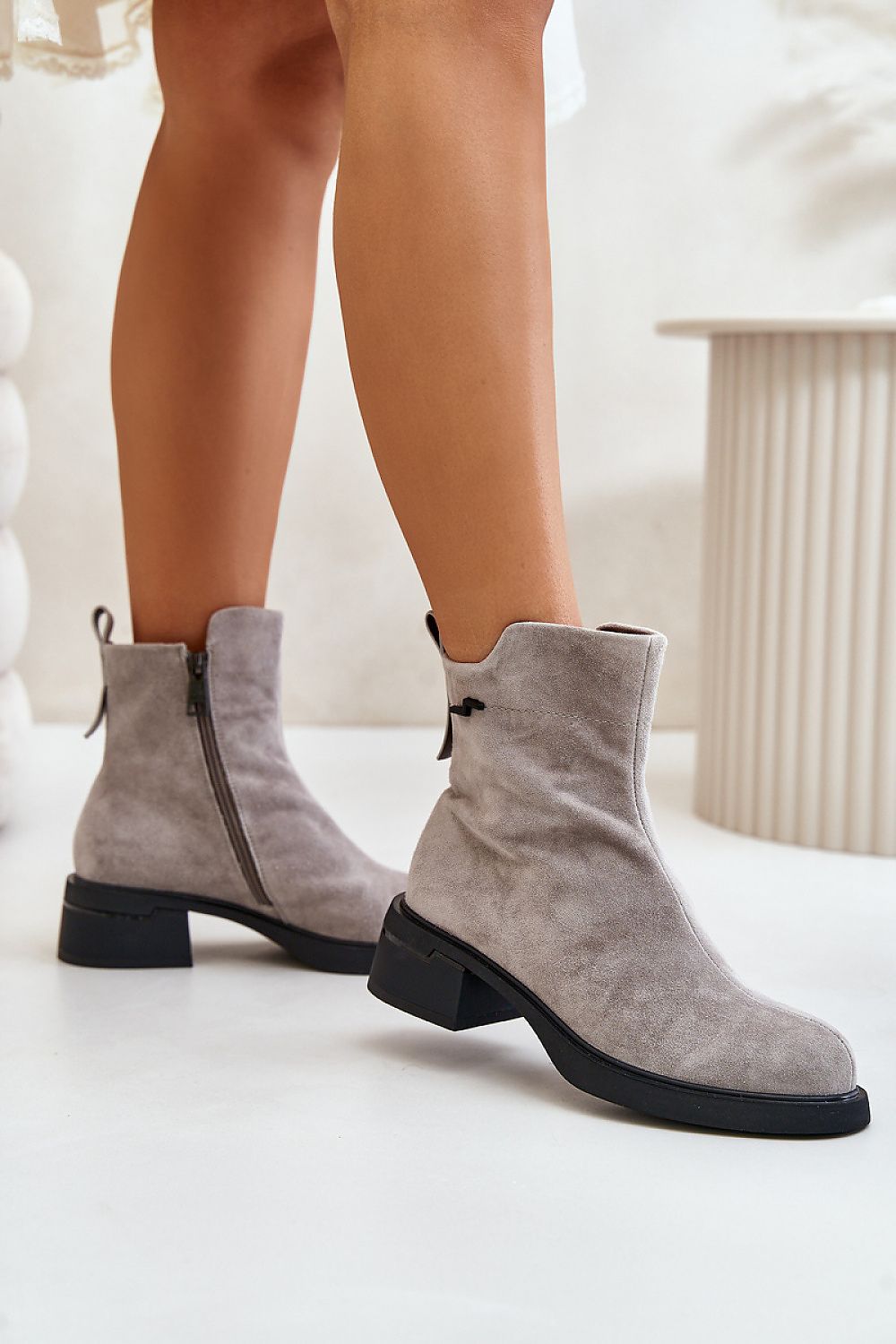 Elegant Veralla Suede Zippered Ankle Boots with rounded toes and metal detail, showcasing cozy lining and mid-height heels, in natural gray suede.