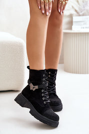 Model wearing black Lindrava Cozy Suede Winter Boots with lace-up design and flat heel, styled with a decorative buckle and soft lining.