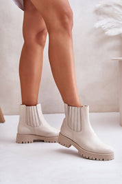 White ankle boots with block heel and elastic sides, worn by model. Ideal for stylish winter fashion.