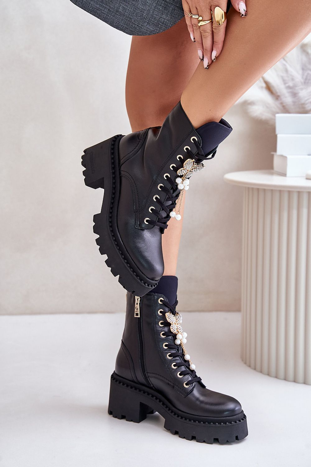 Stylish black combat boots with chunky heels and pearl embellishments for a trendy look.