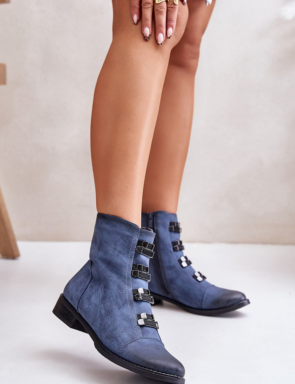 Women's blue ankle boots with buckles and low heel, side view on foot.