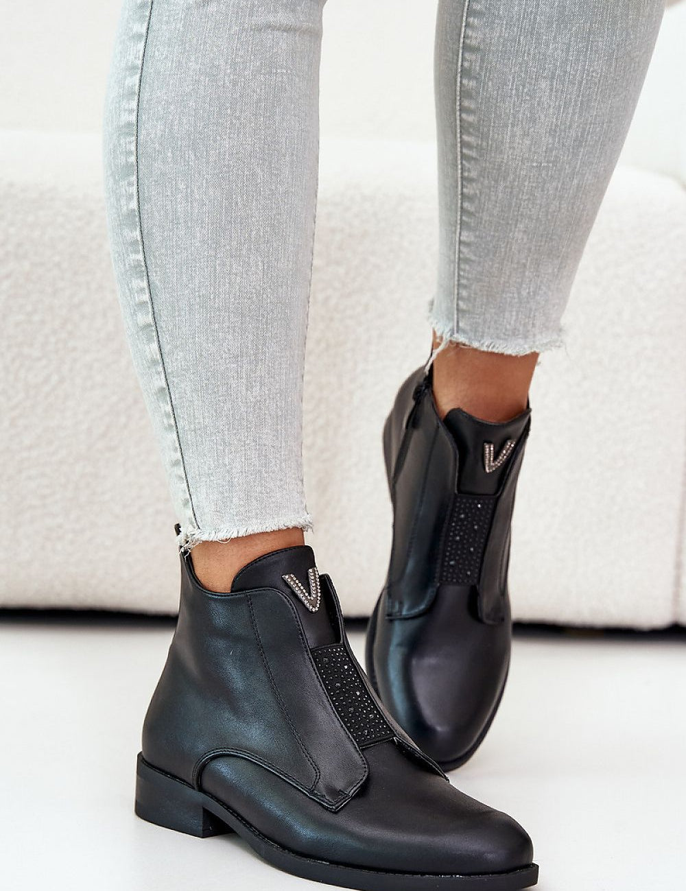 Person wearing Melvaren Zip-Up Ankle Winter Boots in black eco leather with side zipper and decorative tongue element.