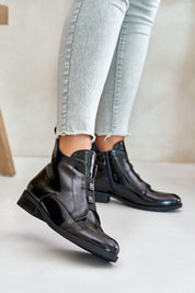 Woman wearing glossy black zip-up ankle boots with skinny jeans, showcasing a chic and modern footwear style.