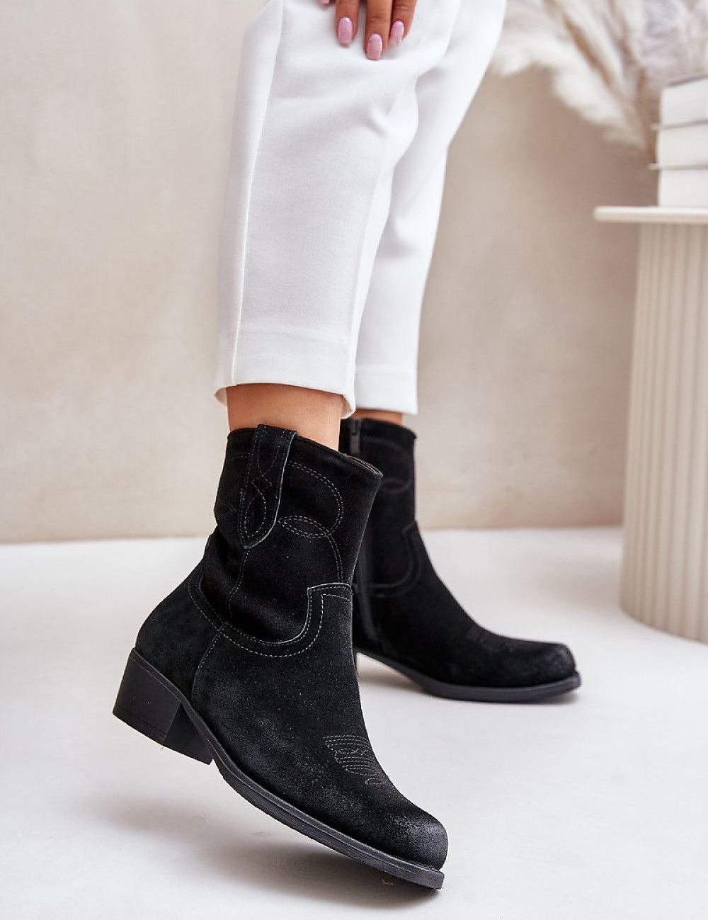 Black suede Western heel boots with square toe, 4.5 cm heel, and stitched detailing, worn by model in white pants.