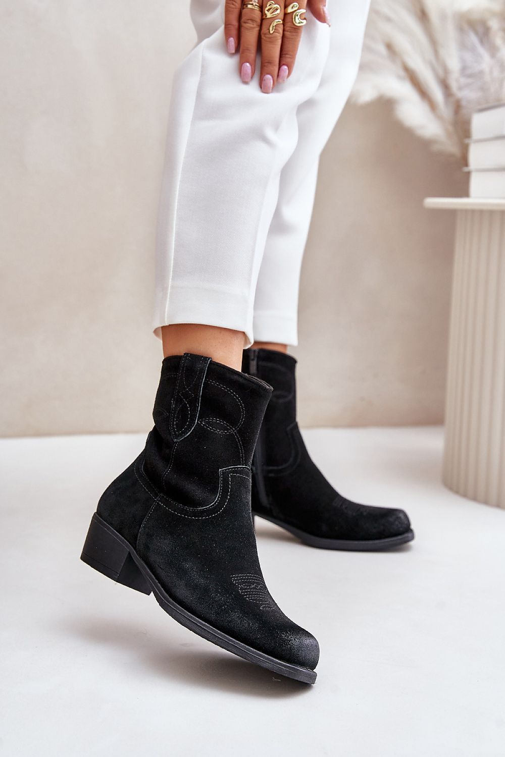Black suede Western heel boots with square toe, 4.5 cm heel, and stitched detailing, worn by model in white pants.