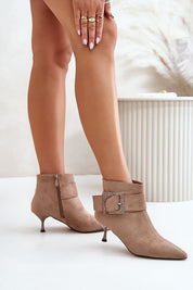 Model wearing Velouryne Bucklash suede heel boots with large buckle and zipper closure.