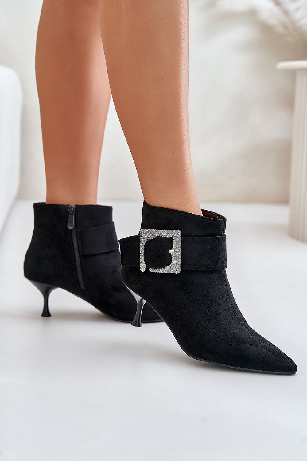 Velouryne Bucklash Suede Heel Boots with pointed toe, large side buckle, and zipper closure, perfect for elegant or everyday wear.