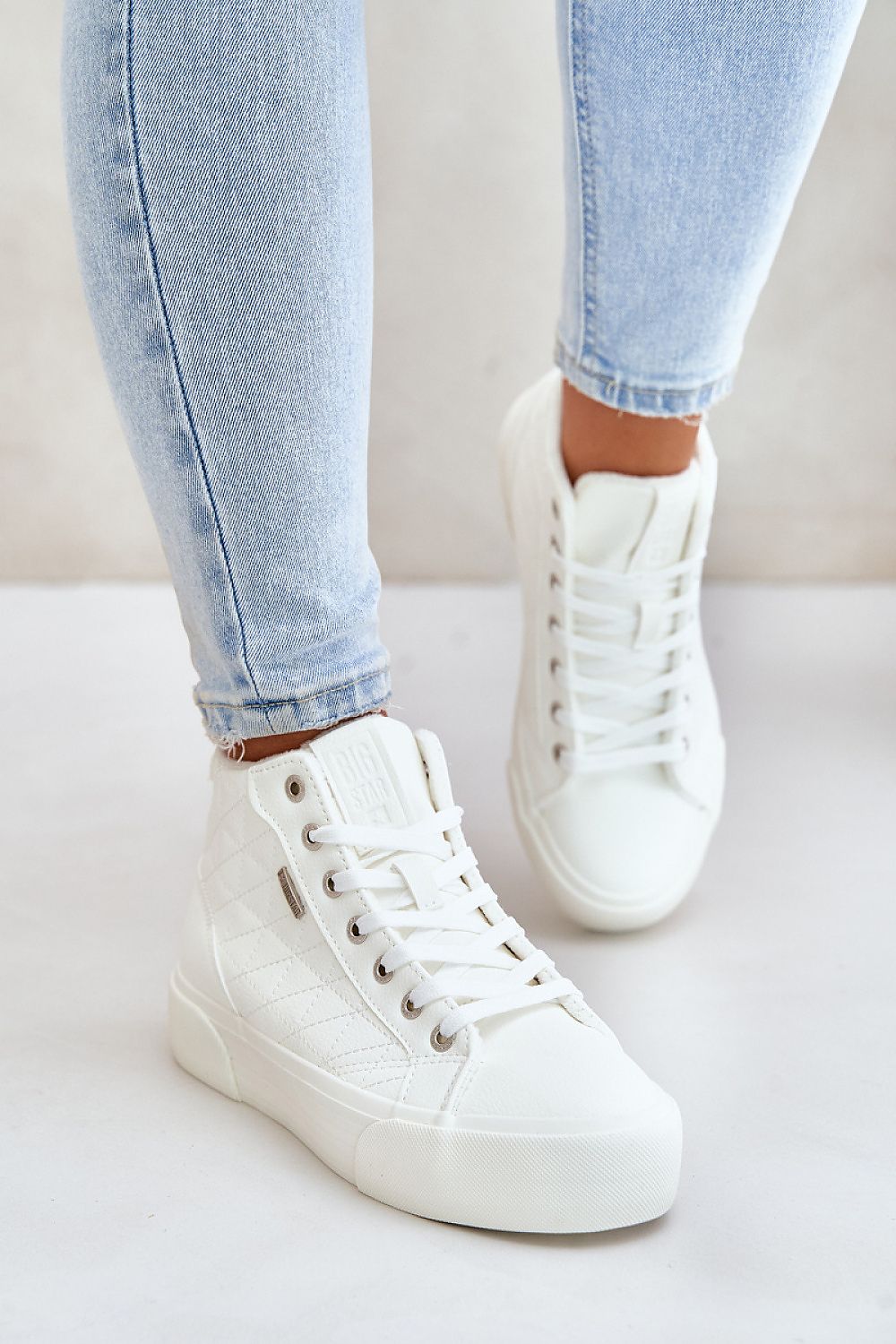 Person wearing Elbrina Insulated Winter Sneakers in white with high-top design and decorative stitching, paired with light blue jeans.