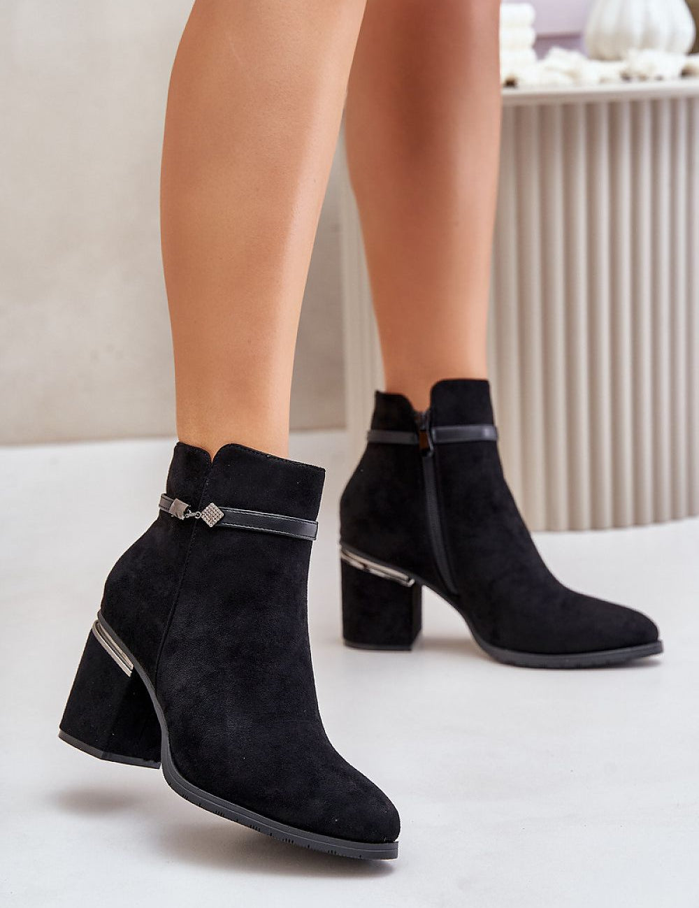 Black suede ankle boots with side zipper and decorative strap, featuring chunky heel and almond toe, styled for autumn wear.