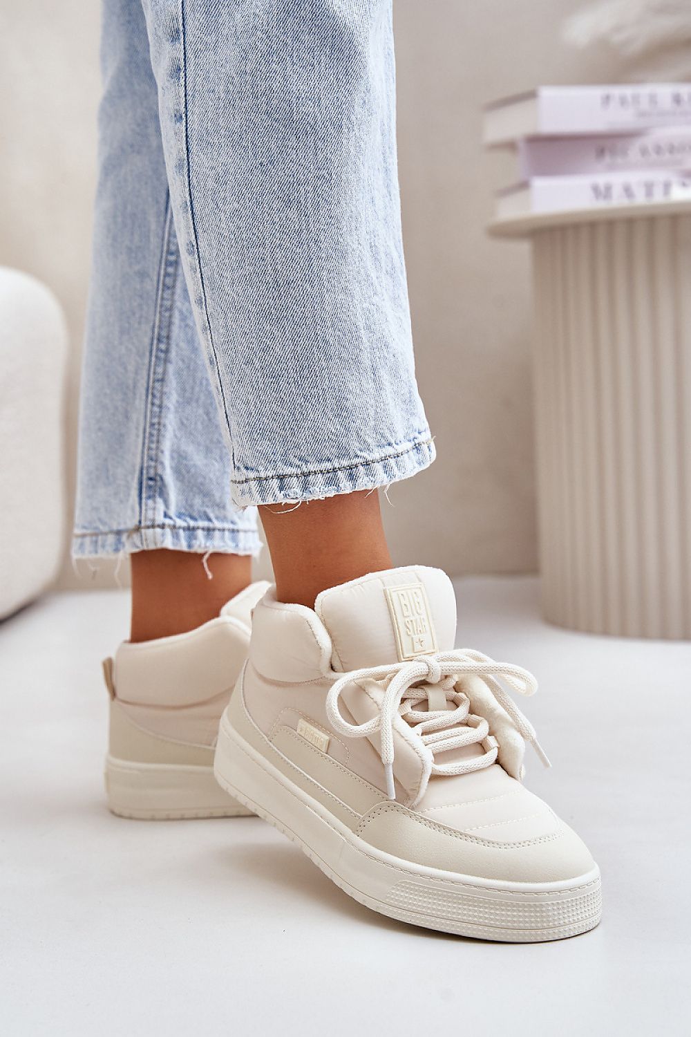 Person wearing Dovema Warm Ankle Sneakers in beige, showcasing durable textile and rubber platform, with jeans in a modern cold-weather outfit.