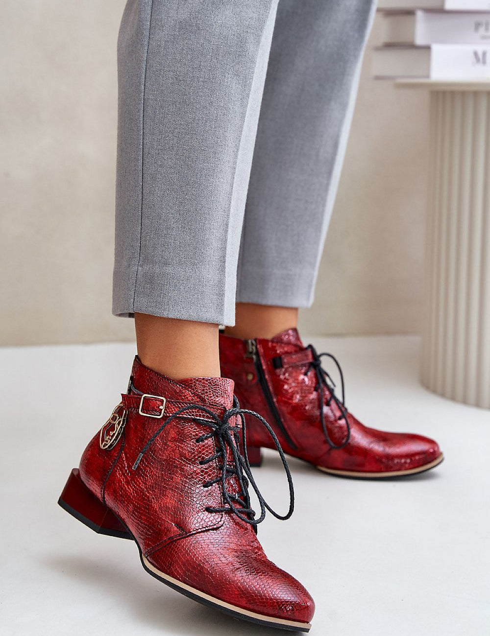 Red Tessara Leather Lace-Up Boots with side detail, worn with gray pants, showcasing stylish design and comfort.