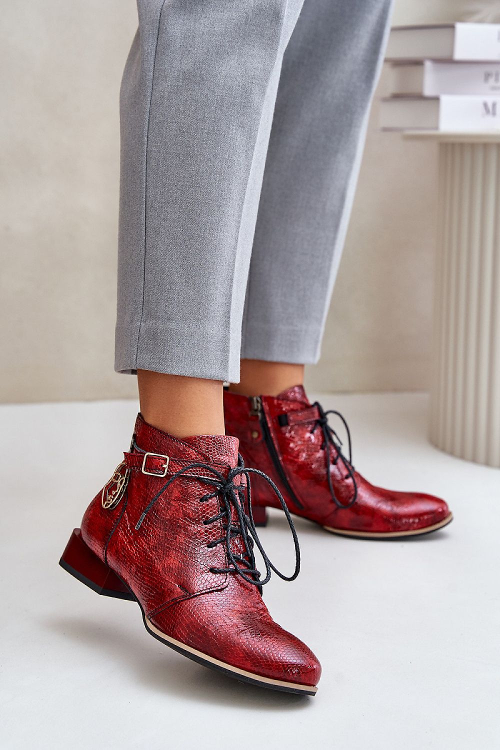 Red Tessara Leather Lace-Up Boots with side detail, worn with gray pants, showcasing stylish design and comfort.