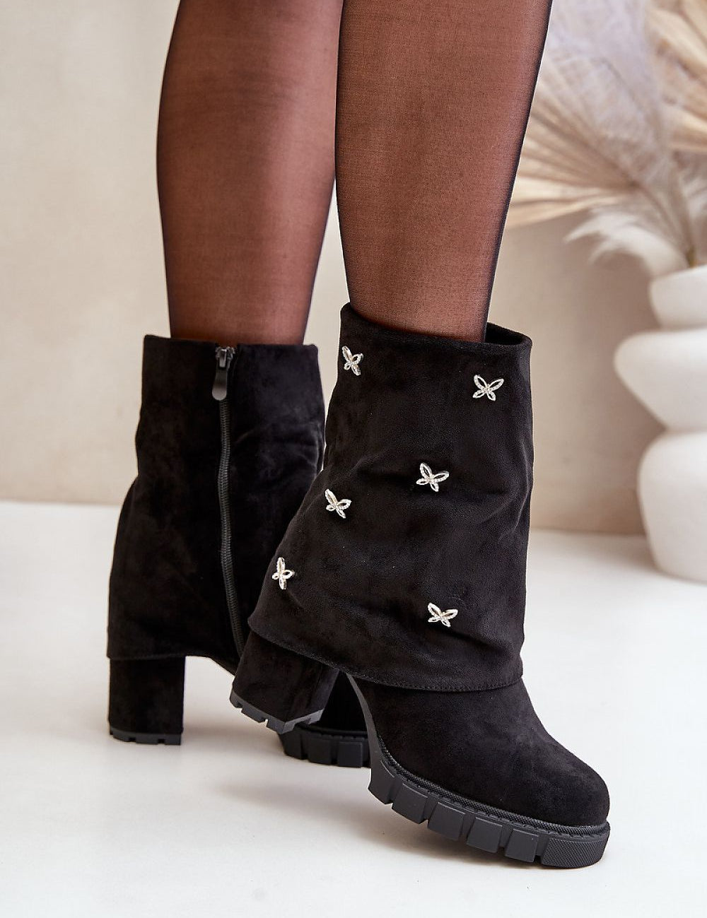 Black suede foldover boots with butterfly accents and side zipper, styled with black tights, perfect for autumn-winter fashion.