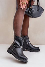 Woman wearing Varita Everyday Ankle Boots in black eco leather with decorative straps, holding a handbag.
