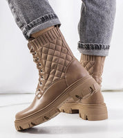 Taupe quilted ankle boots with high trekking-style sole and lace-up closure, paired with cuffed jeans for a stylish look.
