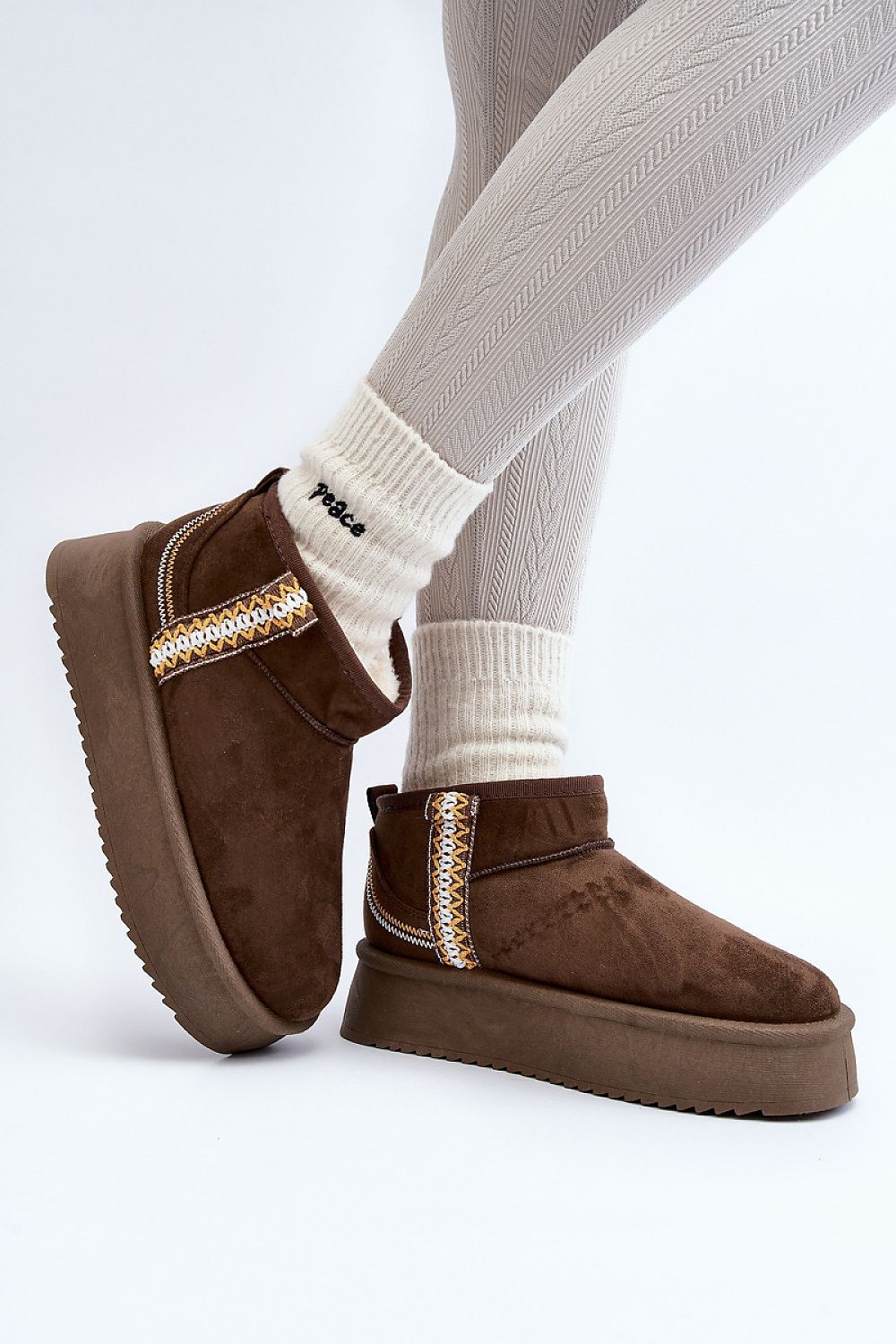 Person wearing Azmira Aztec Platform Snow Boots with Aztec pattern and thick platform, styled with beige tights and socks.