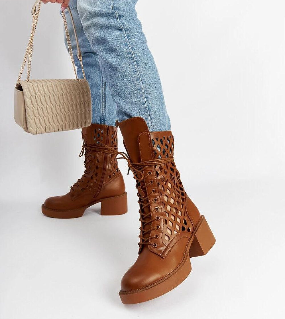 Brown laced ankle boots with heels worn with jeans and a handbag, showcasing stylish winter fashion.