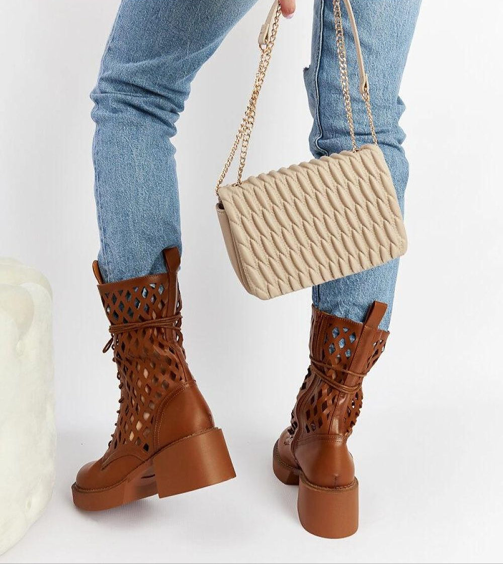 Stylish brown laced ankle boots with a chunky heel paired with a beige quilted handbag, perfect for a chic winter look.