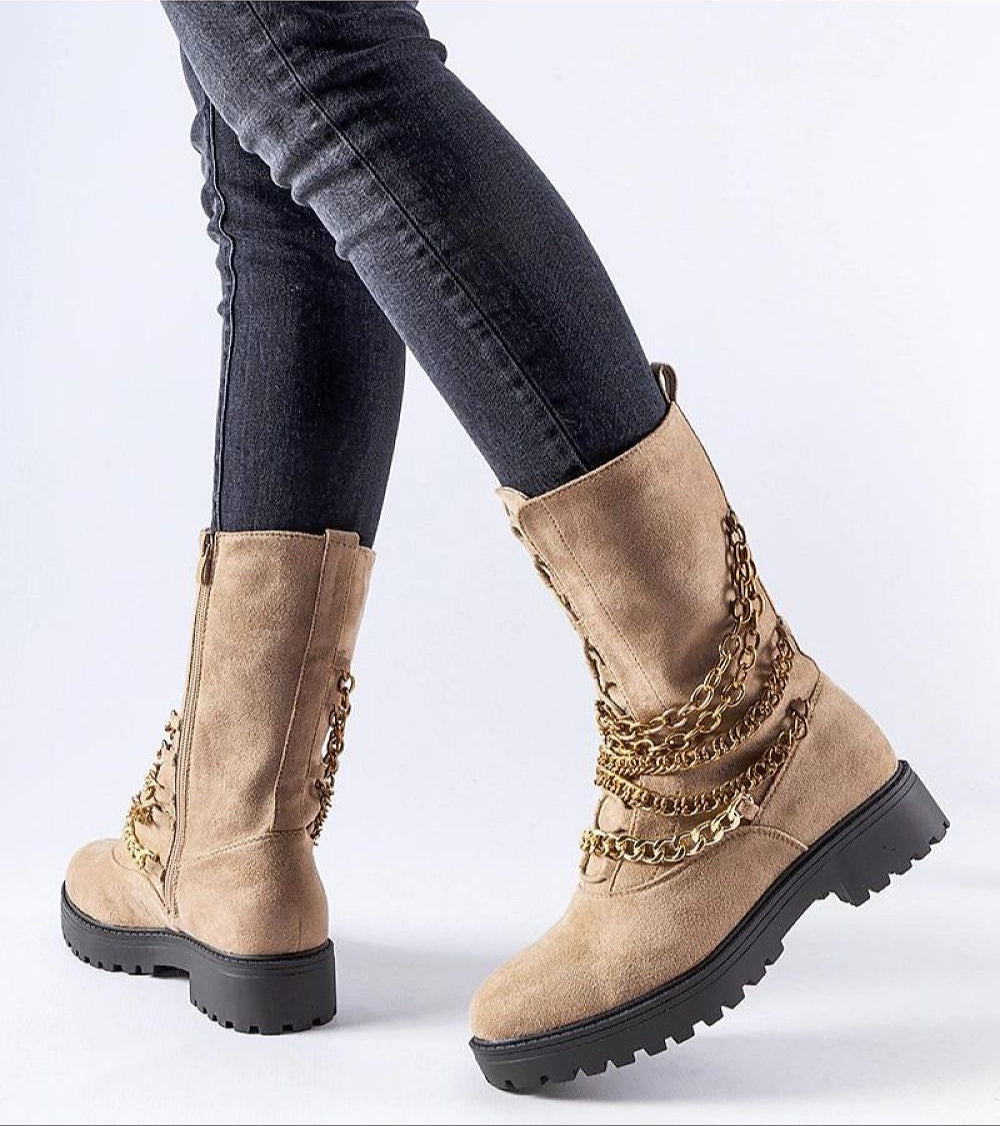 Beige chain-detail ankle boots with black sole, featuring decorative chains, worn with dark jeans.