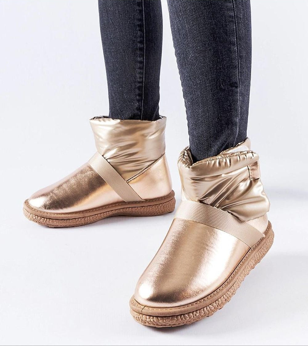 Gold Brivona glossy Velcro snow boots with rounded toe and platform, worn with black jeans, perfect for stylish winter wear.