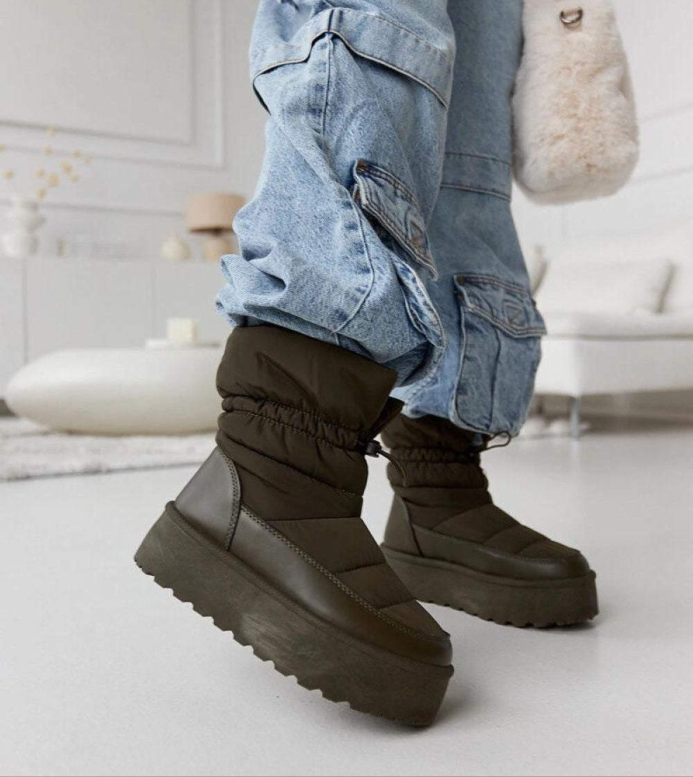 Person wearing Olviera Slip-On Platform Snow Boots with jeans, showcasing stylish winter design and elevated black platform.