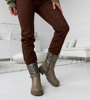 Model wearing Renvara Strap Detail Ankle Boots with brown pants, showcasing insulated design, decorative strap, and side zipper.