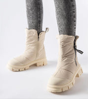 Cream quilted zip snow boots with high shaft and side zipper worn with gray jeans, designed for warmth and comfort in cold weather.