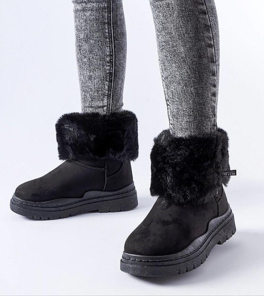 Black Cendara Zip-Up Winter Snow Boots with fur trim, worn with gray jeans, showcasing a warm, stylish option for cold climates.