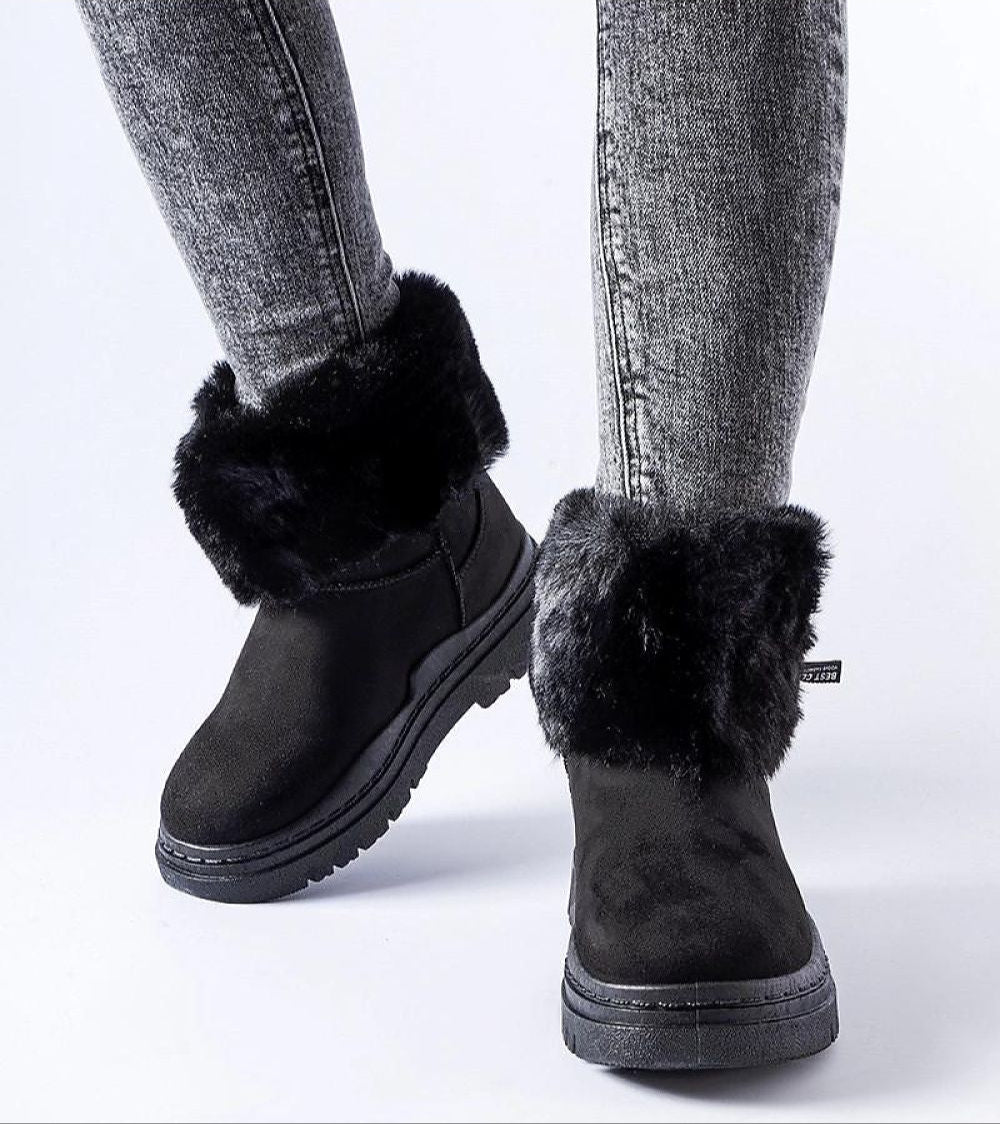 Black Cendara Zip-Up Winter Snow Boots with fur trim and side zipper, worn with gray jeans, ideal for stylish cold-season adventures.