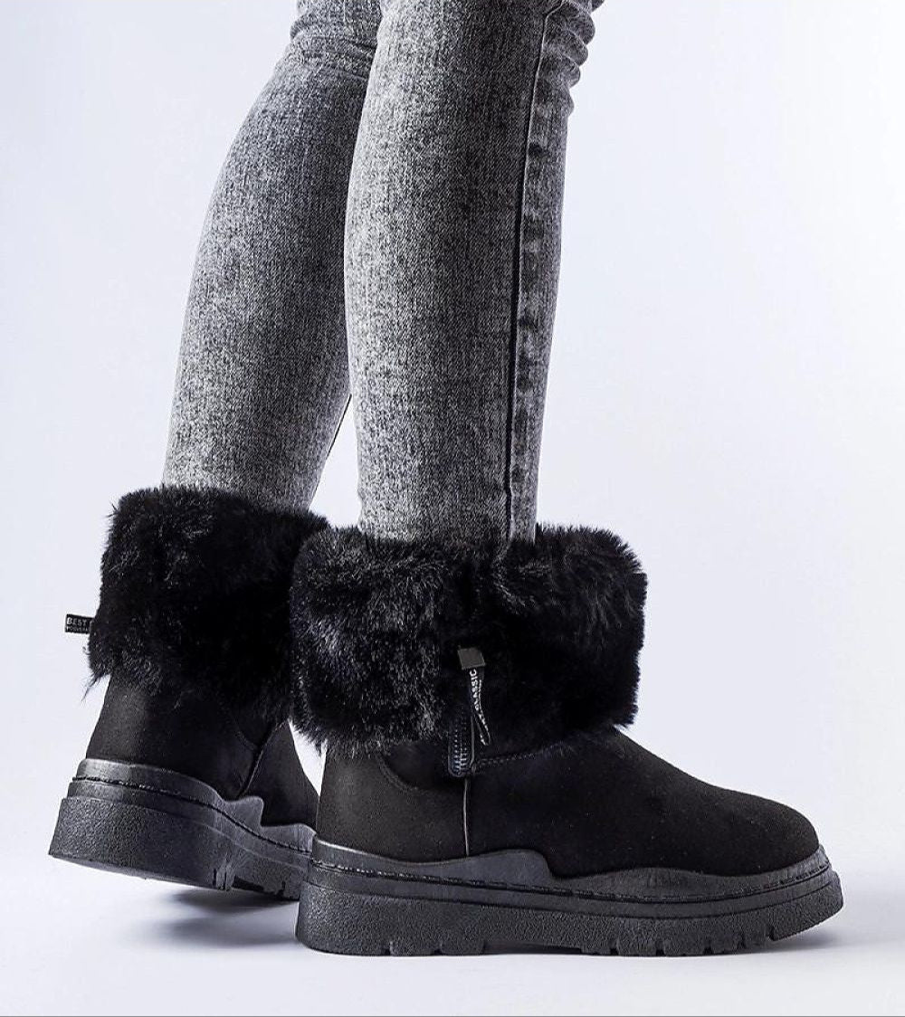 Cendara Zip-Up Winter Snow Boots with fur lining, side view showing sleek black design and textured heel, worn with gray jeans.