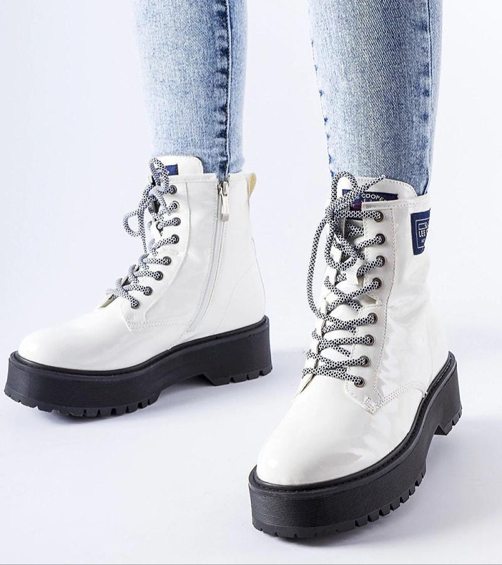 White Alvendra Gloss Ankle Boots with lace-up design and black flat heel, worn with denim jeans, perfect for winter style.