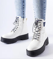 White Alvendra Gloss Ankle Boots with lace-up design and black flat heel, worn with denim jeans, perfect for winter style.