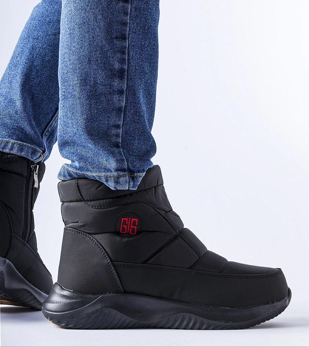 Black Erenelle Short Zip Snow Boots with side zipper, worn with jeans, featuring insulated lining and durable fabric for winter wear.