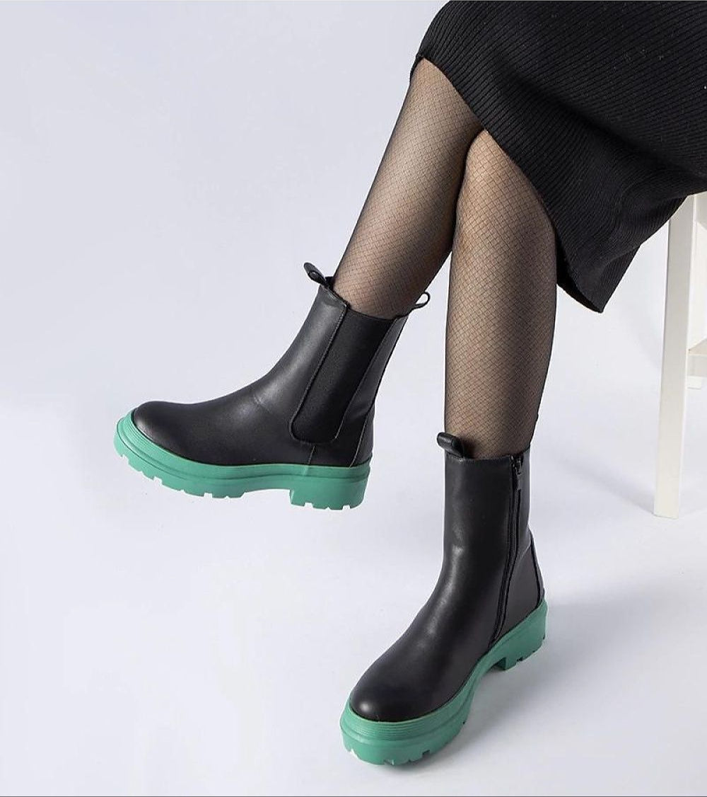 Woman wearing Vereliane ankle boots with olive rubber sole and vegan leather, showcasing modern design and comfort.