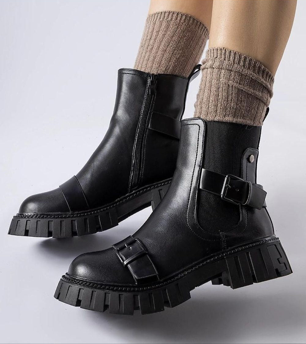 Black insulated heel boots Marvéra with chunky sole and buckles, designed for warmth and style, paired with beige knit socks.