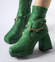 Green square-toe heel boots with pendant detail, showcasing sculptural elegance and fashion-forward design for winter wear.