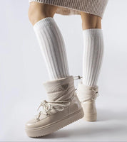 Woman wearing Tharima insulated slip-on snow boots with elevated platform and flexible ankle band for comfortable winter wear.