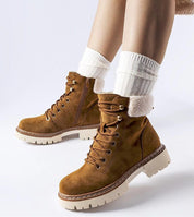 Brown insulated winter trapper shoes with side zipper and rubber sole for grip, modeled with cozy white socks for warm, stylish look.