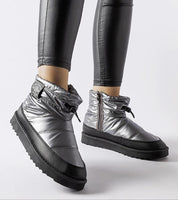 Silver insulated snow boots with side zippers and black rubber soles, paired with black leggings for winter fashion.