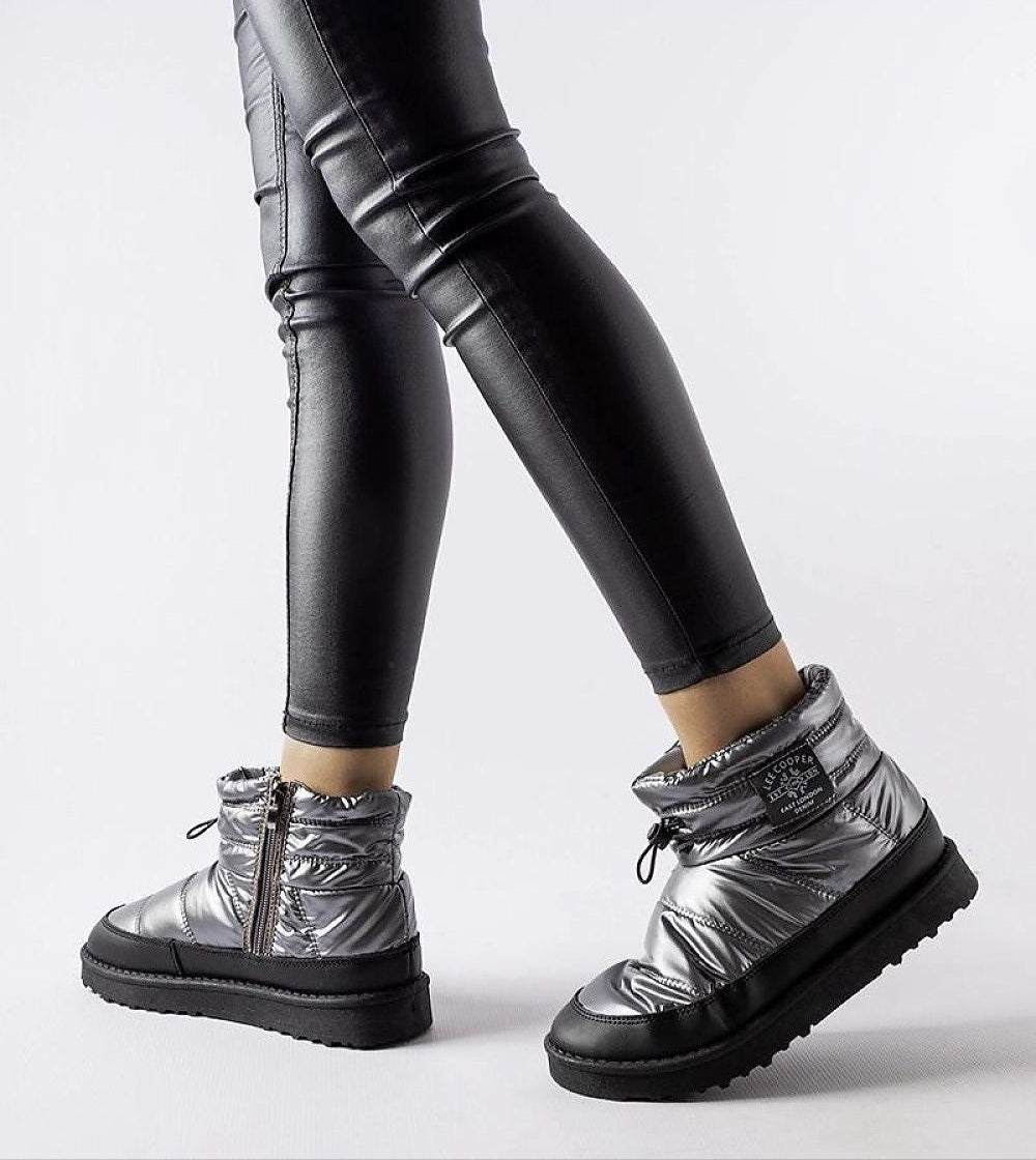 Silver insulated snow boots with side zipper and black rubber sole, worn with black leggings for a sleek winter look.