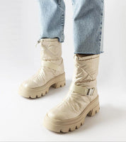 Beige winter snow boots with buckle detail and chunky sole, paired with blue jeans
